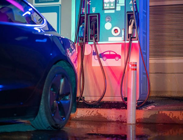 Charging pile with chargers and part of black electric car Charging pile with chargers and part of black electric car standing in front