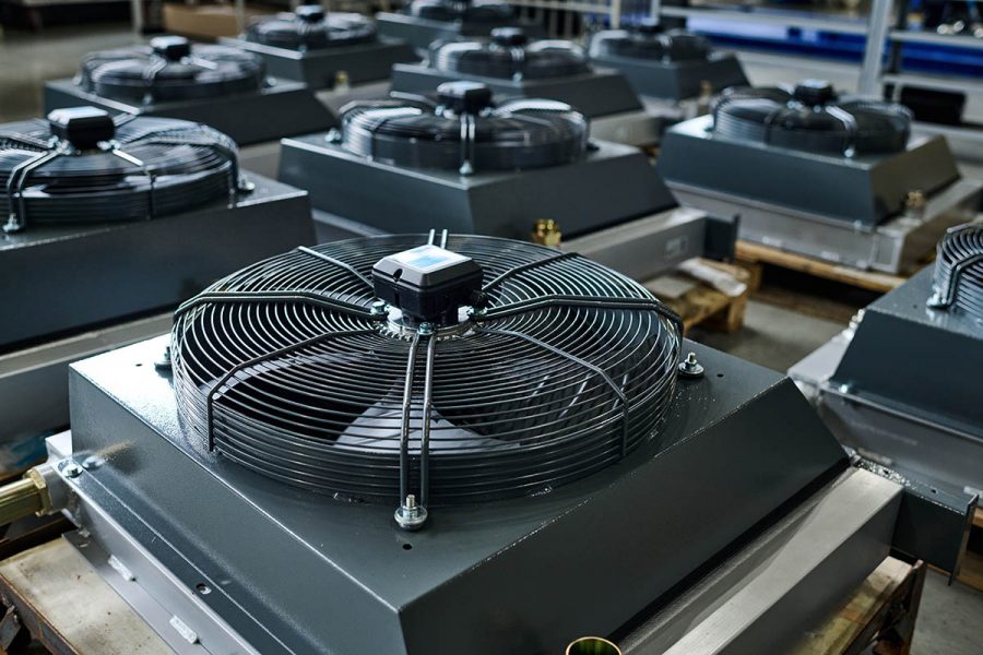 Group of new industrial equipment or parts of huge machines on wooden crates in spacious workshop or warehouse of modern factory